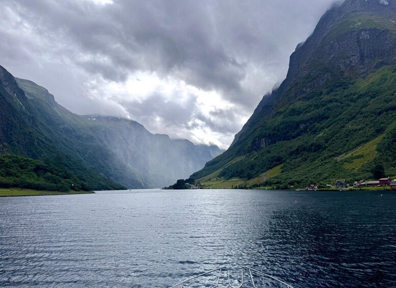 A fjord with steep cliffs, calm water, and a cloudy sky. 2