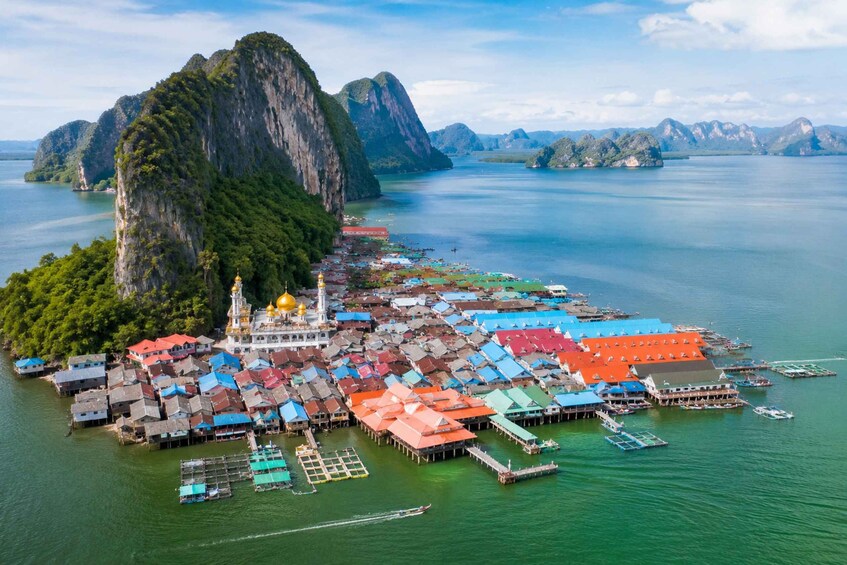 A coastal village with colorful houses, a prominent golden-domed temple, and a large mountain in the background. 4