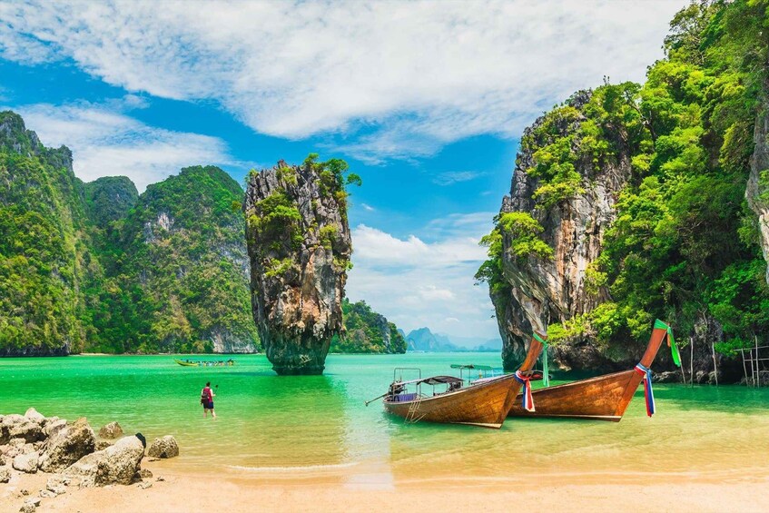 A beach with boats, clear turquoise water, and limestone cliffs. 3