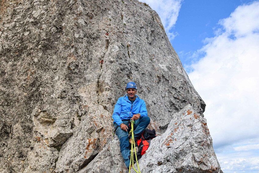 A person sitting on a rock with a climbing rope. 3