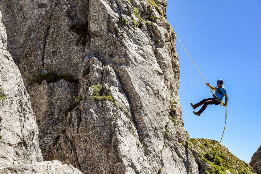 A person rappelling down a rocky cliff. 2