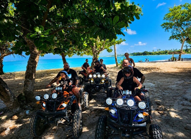 A group of people on ATVs on a sandy beach with palm trees and a clear blue sea in the background. 4