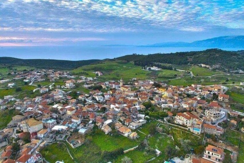 A coastal town with a mix of residential and historical buildings, surrounded by green hills and the sea. 2