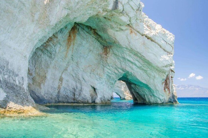 A white rock formation with a natural arch over turquoise water. 4