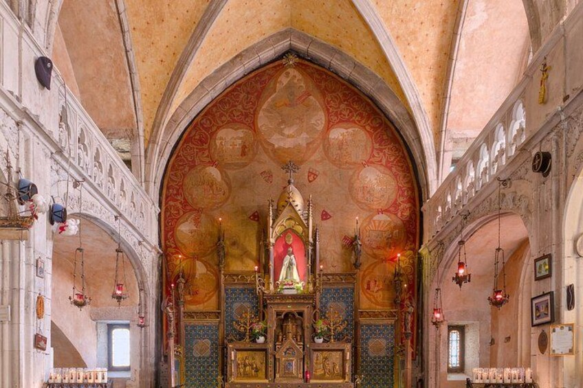 An ornate church interior with a central altar, arched ceilings, and religious icons. 3