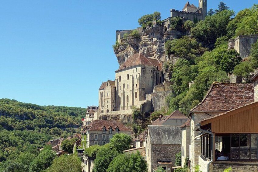 A historic castle on a hill, surrounded by lush greenery and traditional buildings. 1
