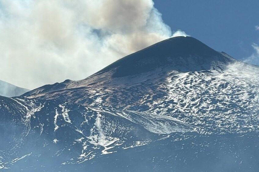 A snow-covered mountain with a plume of smoke rising from its peak. 3