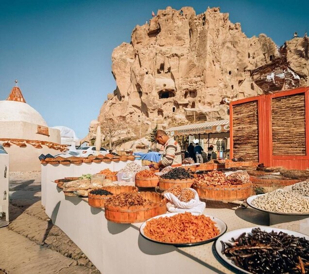 A food stall with various dishes in front of a rocky cliff. 3
