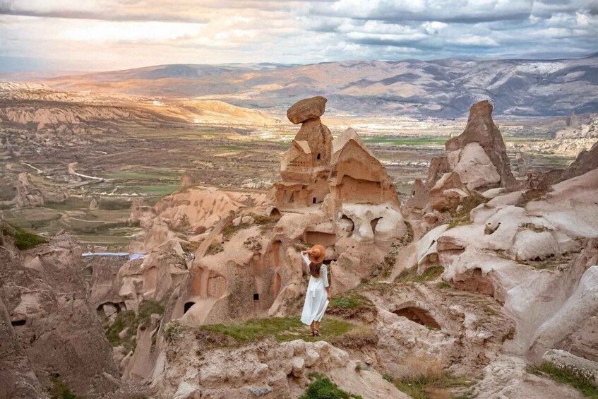A person standing on a rocky outcrop with a desert landscape and mountains in the background. 4