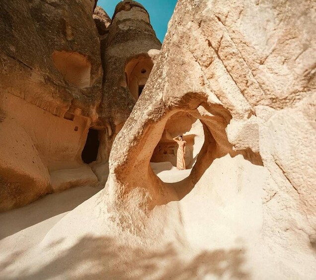 A person standing in a natural rock formation with a cave-like opening. 1