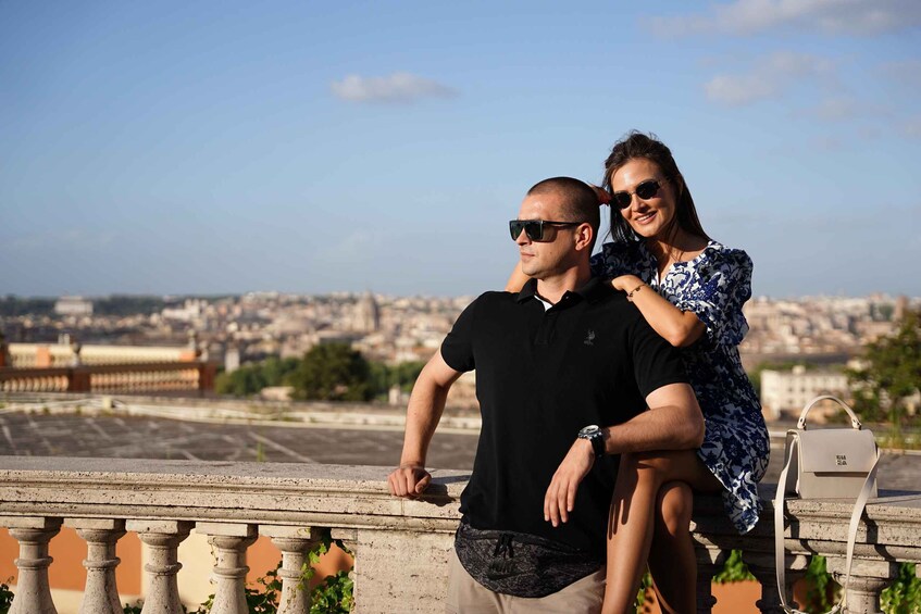 A couple on a balcony overlooking a cityscape with buildings and a clear sky. 3
