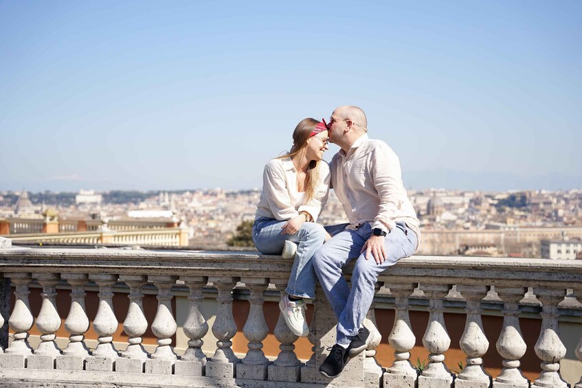 A couple sitting on a balustrade overlooking a cityscape. 2