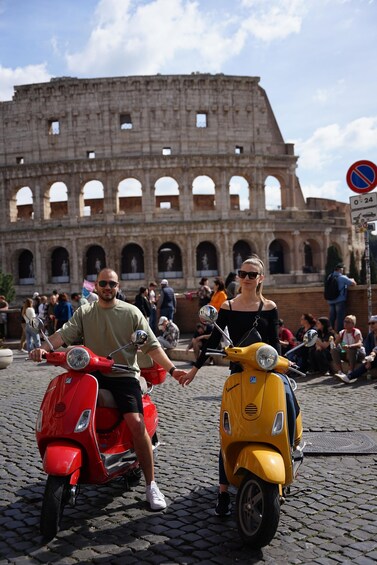 Two people on scooters in front of the Colosseum. 1