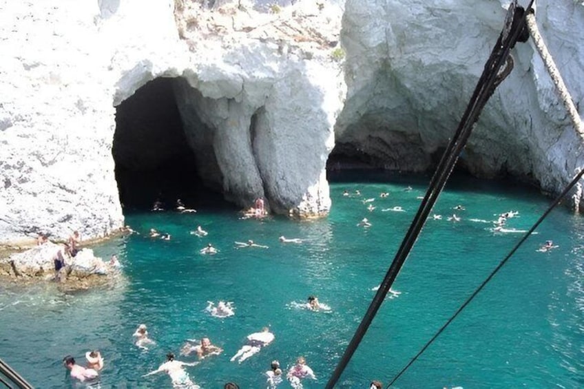A group of people swimming in a turquoise pool with white rock formations in the background. 3