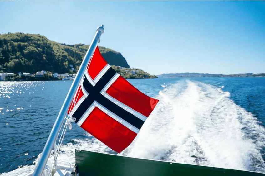 A Norwegian flag on a boat, water, and a distant shoreline. 3