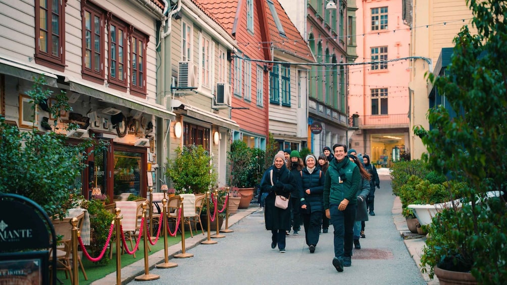 A group of people walking down a cobblestone street lined with historic buildings and potted plants. 4