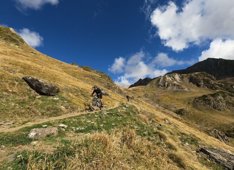 A mountain biking trail with rocky terrain and grassy slopes. 1