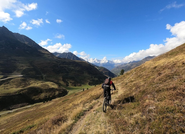 A mountain biker on a trail with a valley and mountains in the background. 1