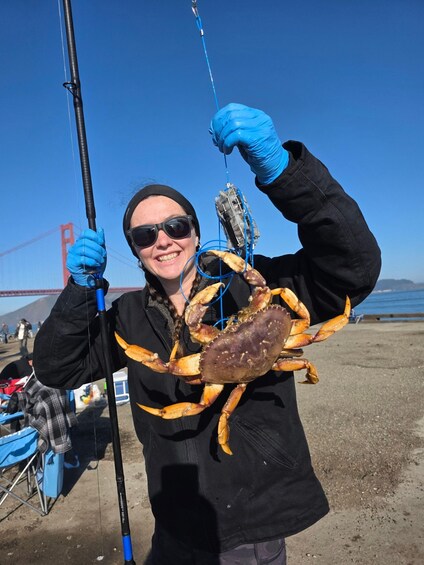A person holding a large crab with a fishing rod. 1