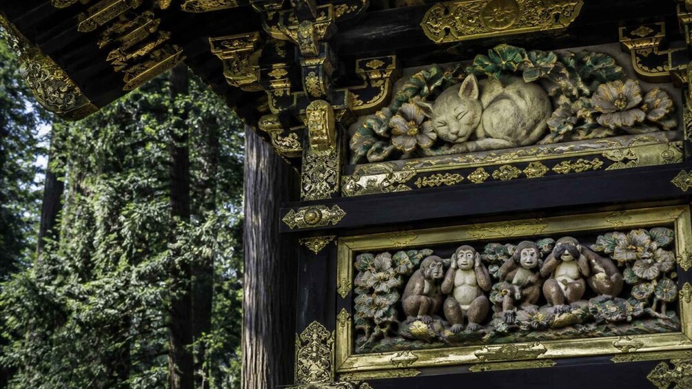 A detailed black and gold architectural structure with intricate carvings, including a prominent lion figure and a row of seated figures. 4