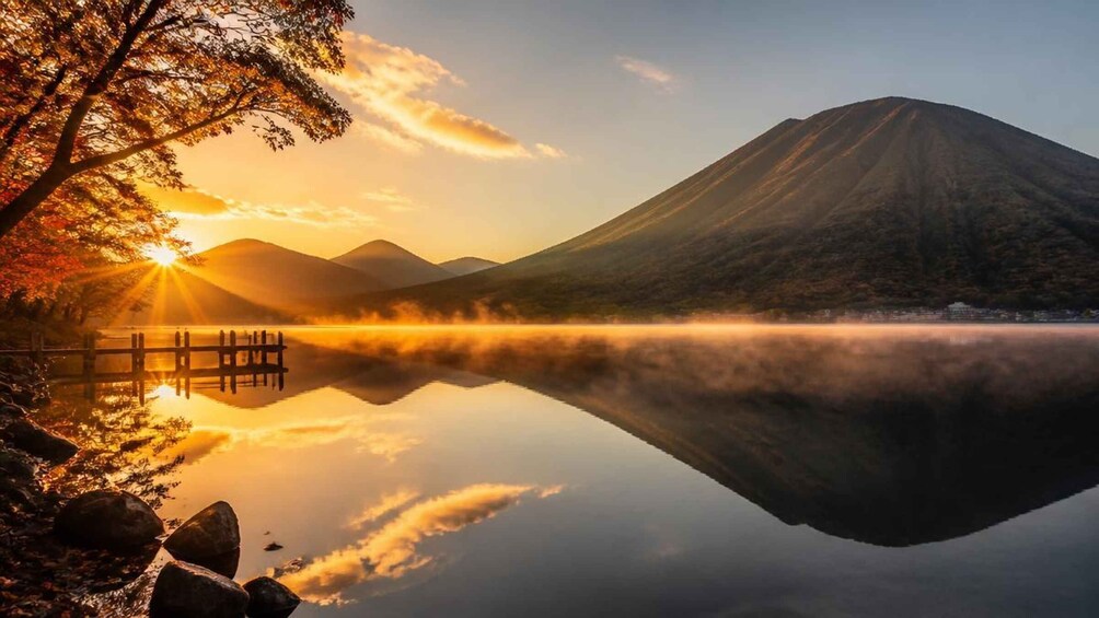 A mountain lake at sunrise with a wooden dock and autumn trees. 5