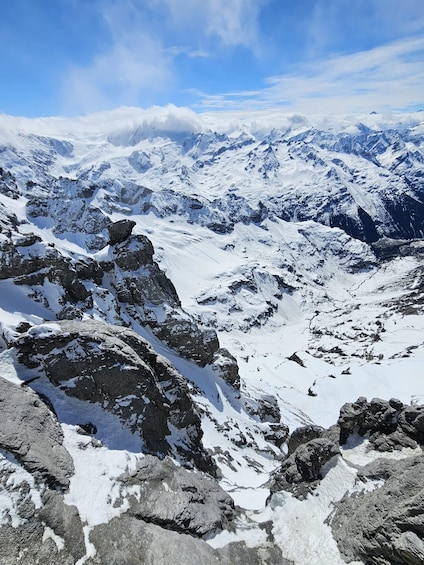 A snow-covered mountain range with rocky outcrops and a clear blue sky. 3