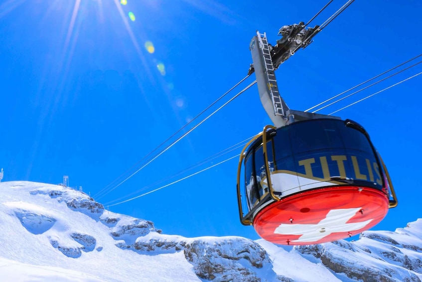 A cable car labeled 'TITLIS' suspended above a snowy mountain landscape. 4