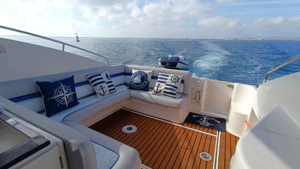 A boat's deck with a cushioned seating area, nautical-themed cushions, and a view of the open sea. 2