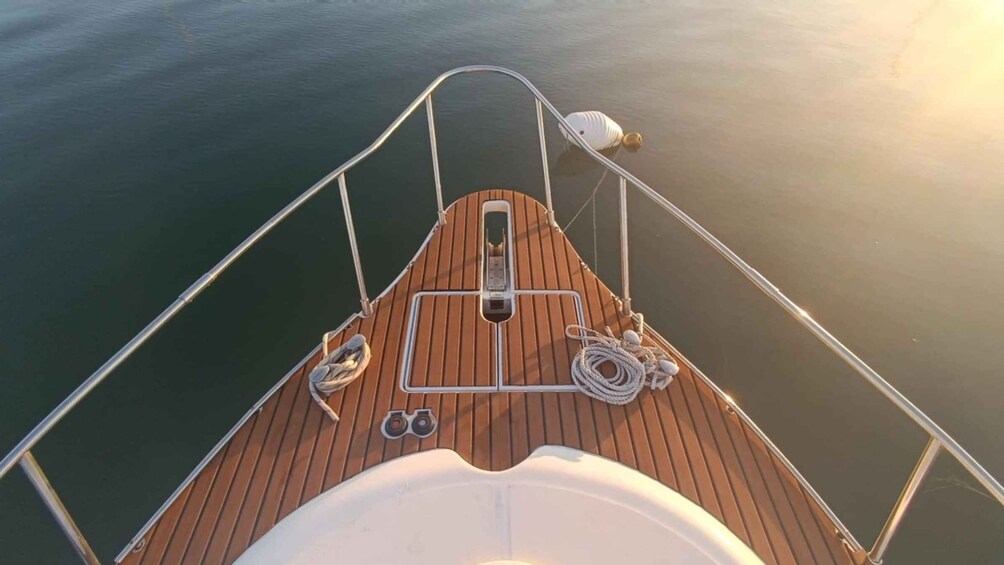 A boat's deck with a wooden floor, metal railings, and a white cabin structure. 3