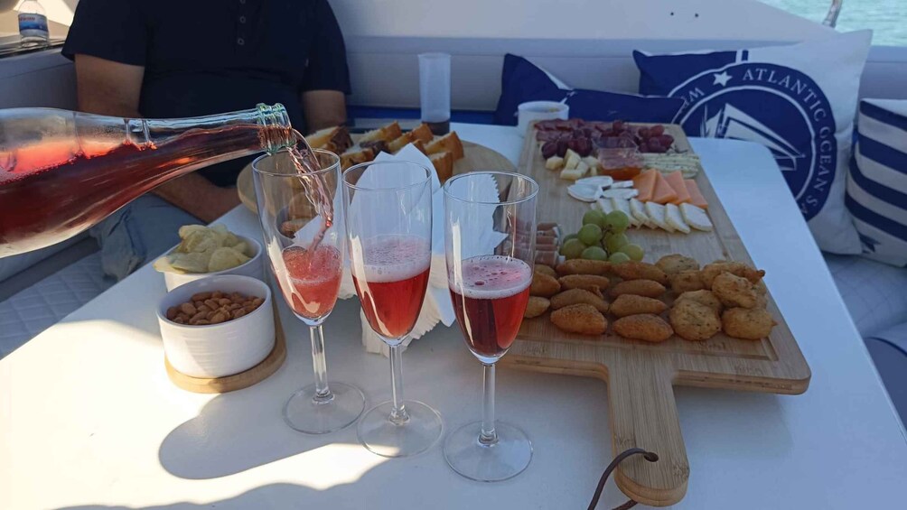 A boat with a table set for a meal, including a bottle of red wine being poured into glasses. 4