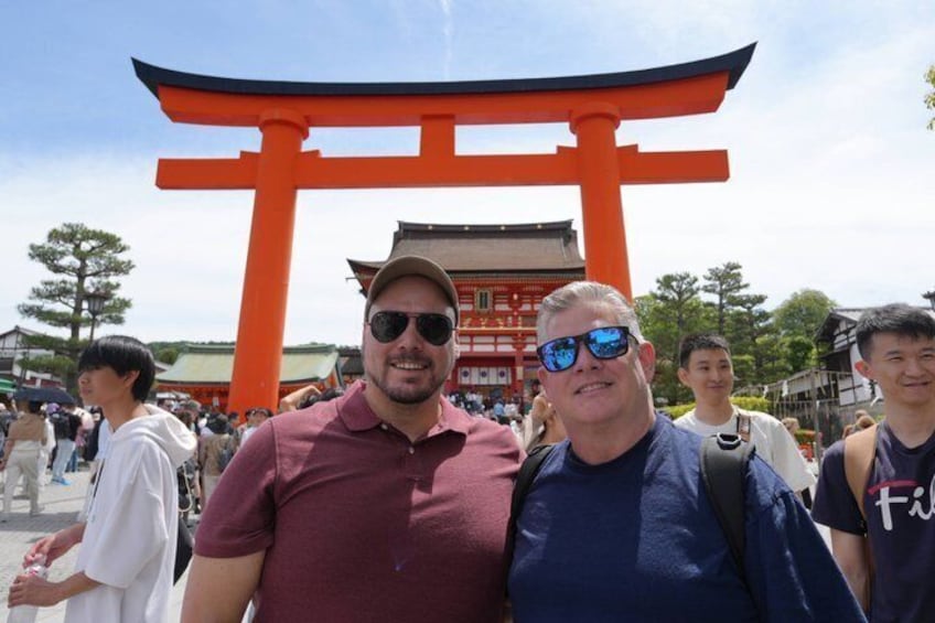 A group of people standing in front of a large orange torii gate. 5