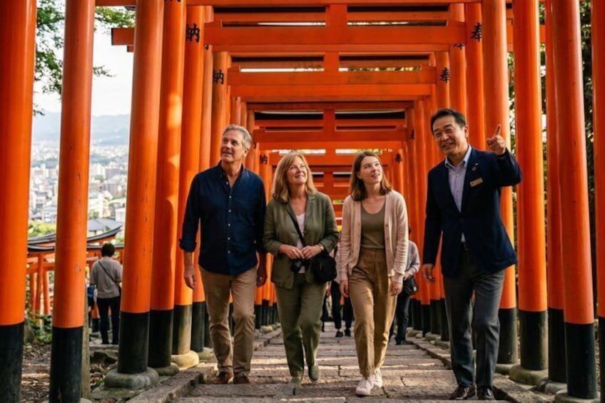 A group of people walking through a corridor of orange torii gates. 1