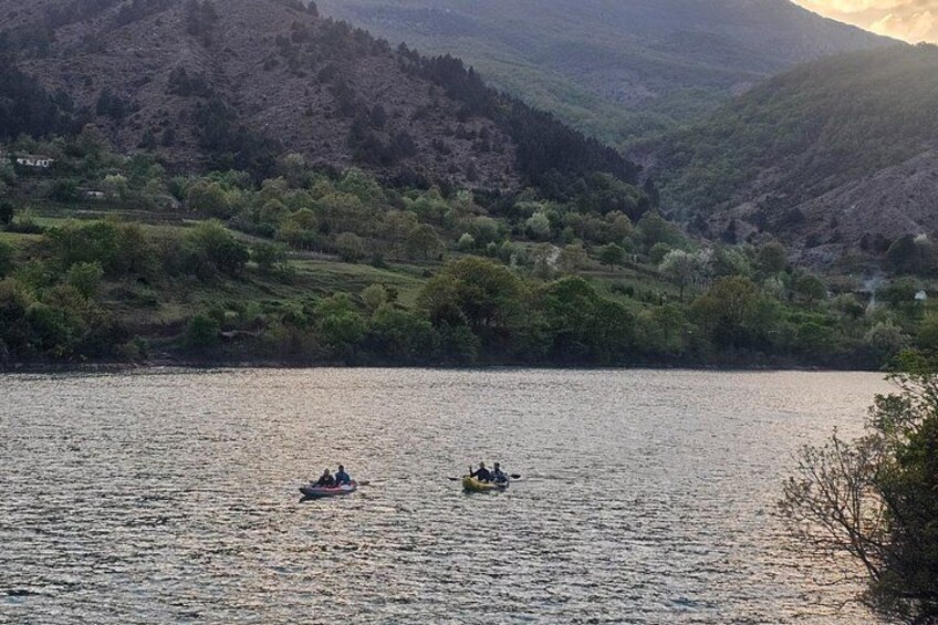 A calm lake with two boats, surrounded by lush green hills. 2