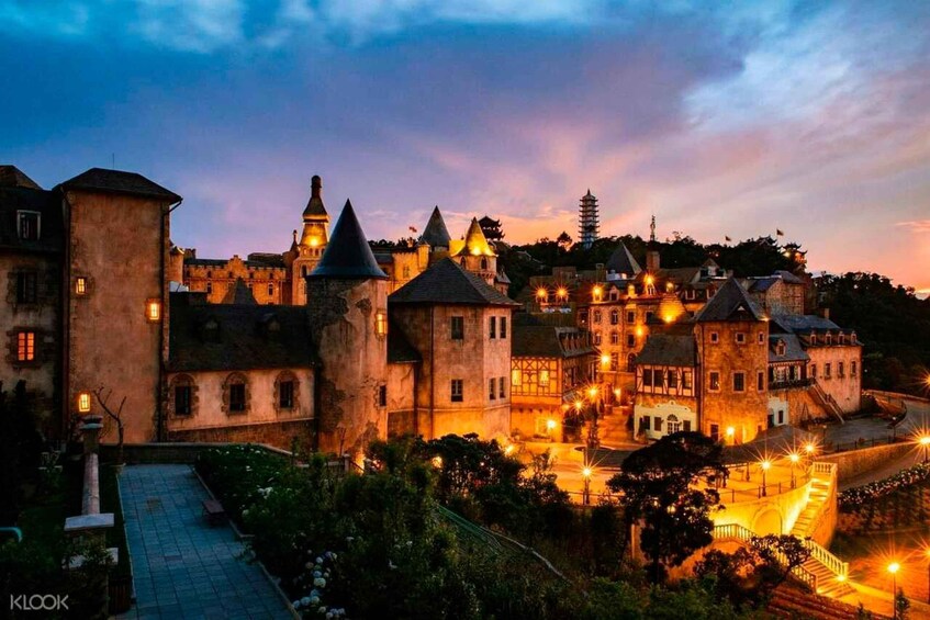 A historic castle complex at dusk with illuminated towers and a well-maintained courtyard. 4