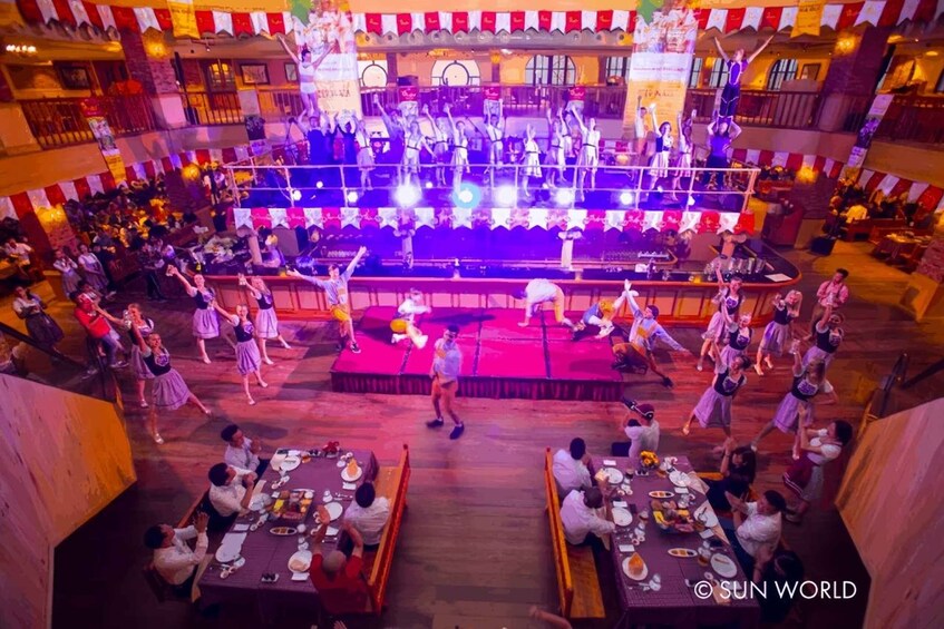 A group performing on a stage in a restaurant with patrons seated at tables. 5