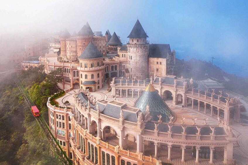 A large, ornate castle with multiple towers and a red cable car on a track. 2