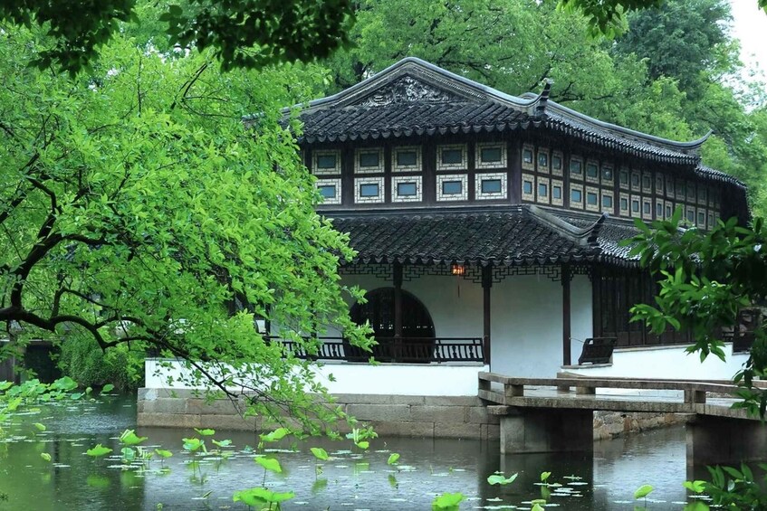 A traditional building with a tiled roof, surrounded by lush greenery and a calm water body with lily pads. 4