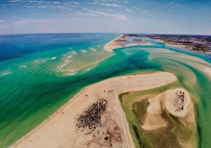 An aerial view of a coastal landscape with clear blue waters, sandy beaches, and a distinct green lagoon. 2