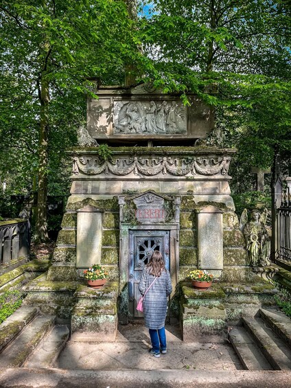 A stone monument with a carved relief, a name plaque, and a statue of an angel. 1