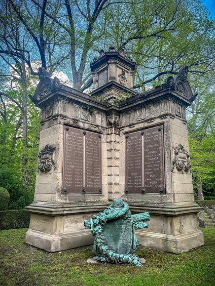 A stone monument with inscriptions and a bronze statue of a figure. 2