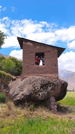A stone structure with a flat roof, perched on a large rock. 2