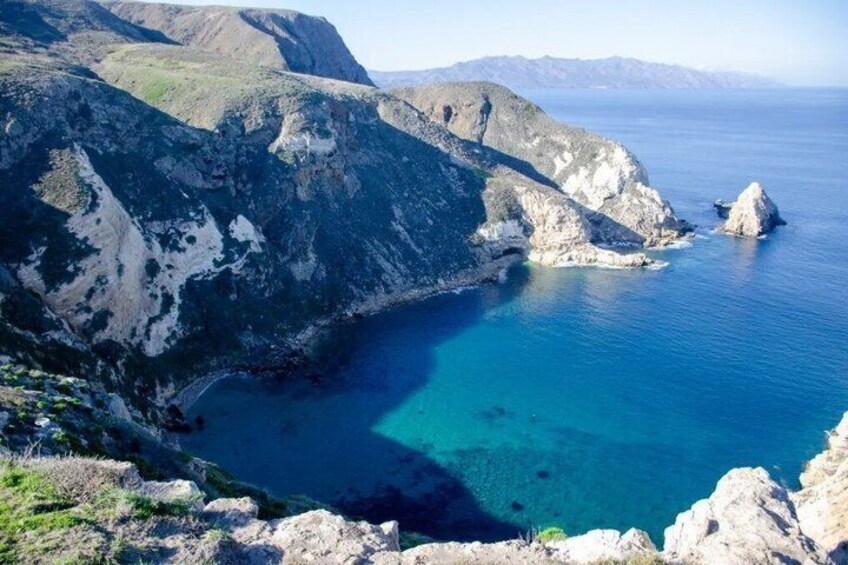 A coastal landscape with rocky cliffs and clear blue waters. 3