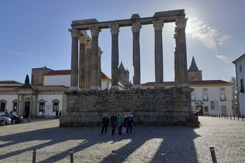 Ancient ruins with columns, a cobblestone ground, and a clear sky. 1