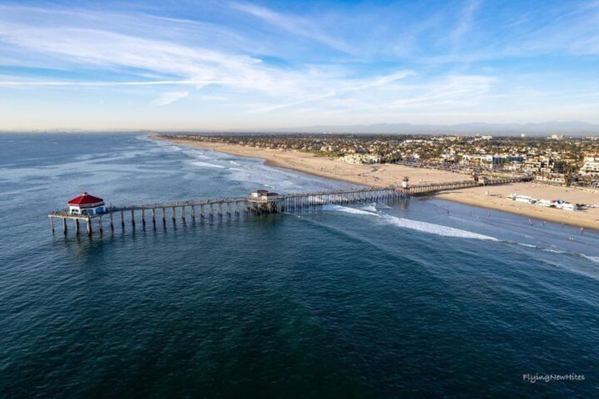 A coastal pier extending into the ocean with a lighthouse on the left and a beach on the right. 3