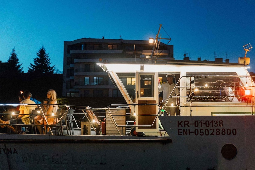 A boat with people on deck, a building in the background, and a clear sky. 5