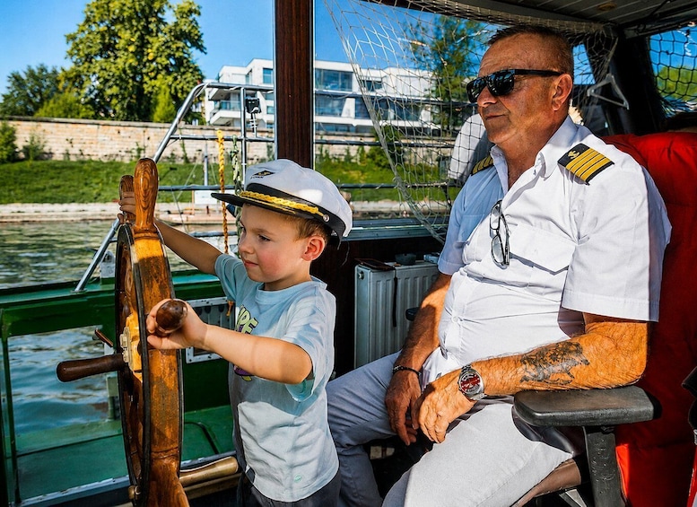A man in a white uniform with a watch and a young boy in a blue shirt holding a wooden oar on a boat. 4