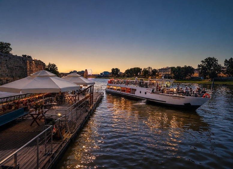 A river with a boat docked at a wooden pier, a Ferris wheel in the background, and a sunset. 1