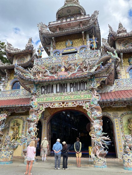 Ein Tempelportal mit aufwendigen Drachenskulpturen und einem Schild mit der Aufschrift 'CHOA LING PHUOC'. 2