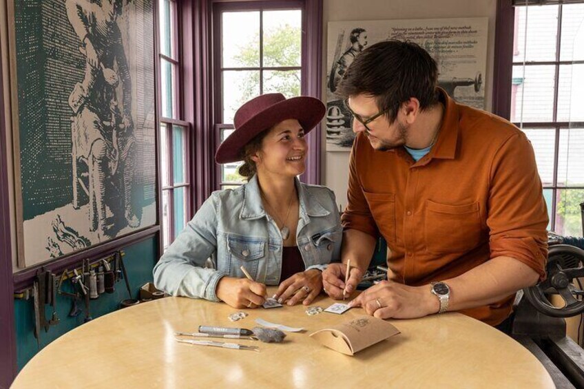Two people at a table with tools and a map, in a room with windows and a large poster. 1