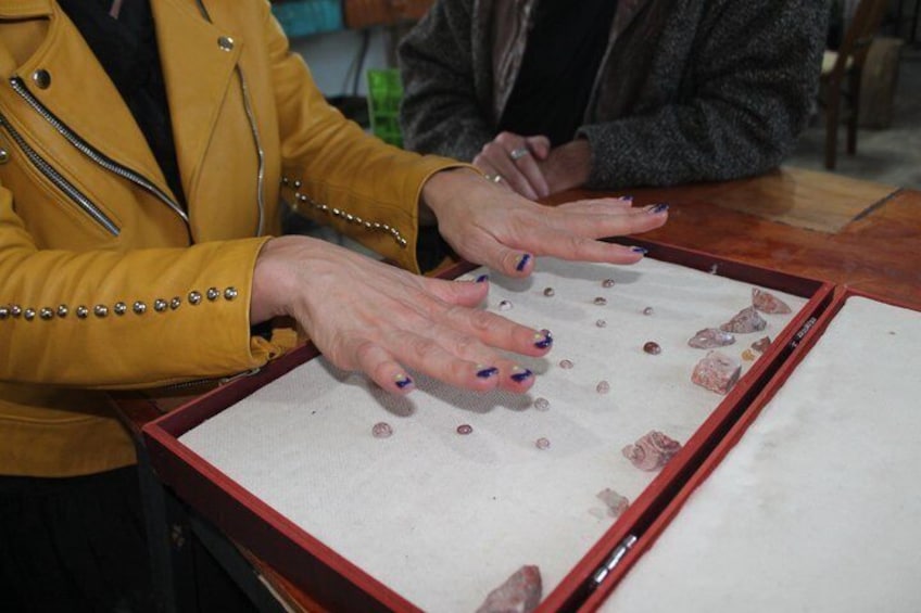 A person in a yellow jacket handling a framed display of small objects. 4